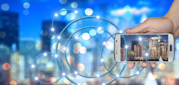 image of hand holding phone with picture of city. blurred city is behind the image